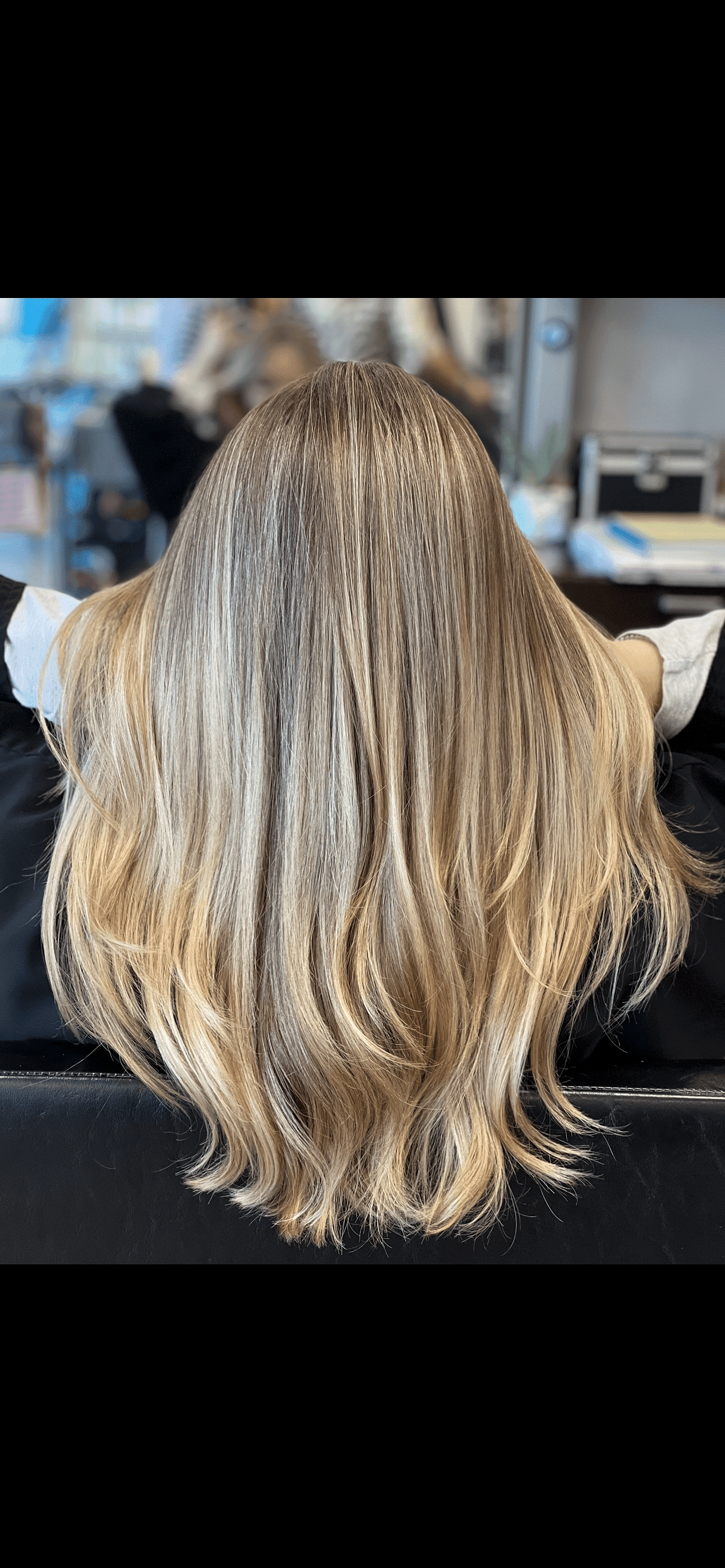 Long, straight blonde hair with subtle highlights at a hair salon.