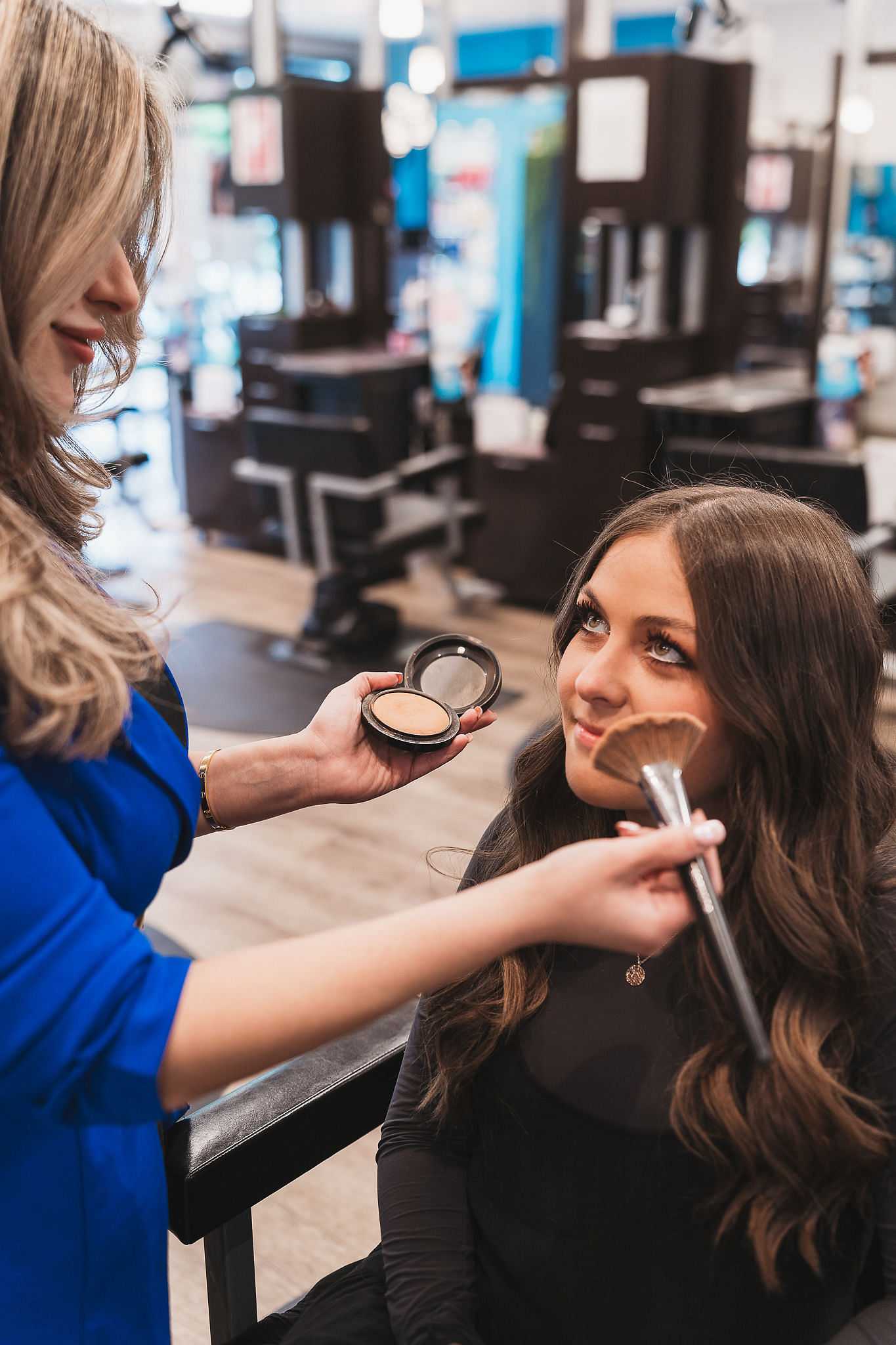 Woman getting her makeup done by a stylist in a beauty salon.