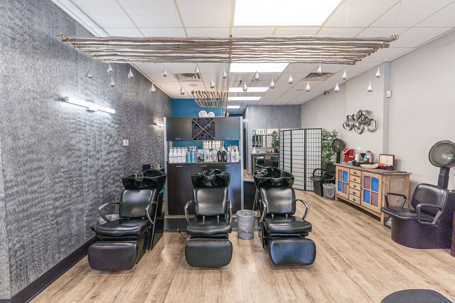 Modern hair salon with three black washing stations, stylish decor, and wooden flooring.