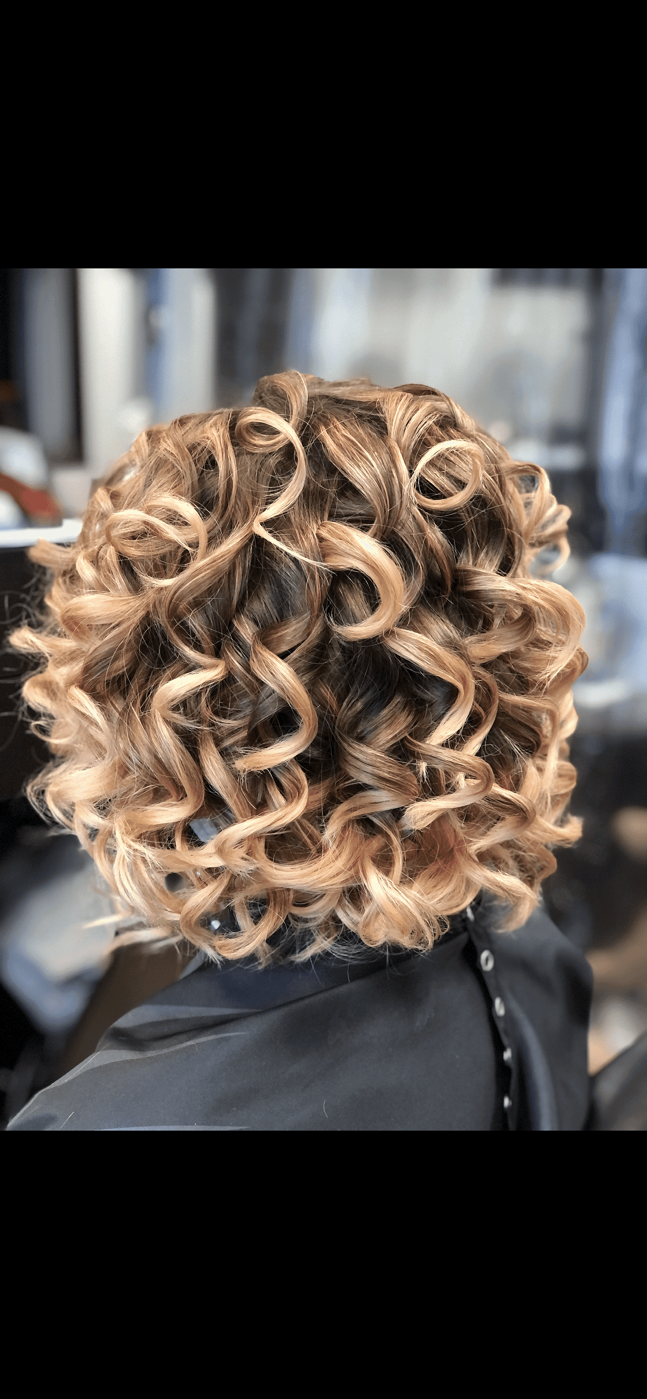 Close-up of styled hair with blonde ringlets and curls in a salon setting.