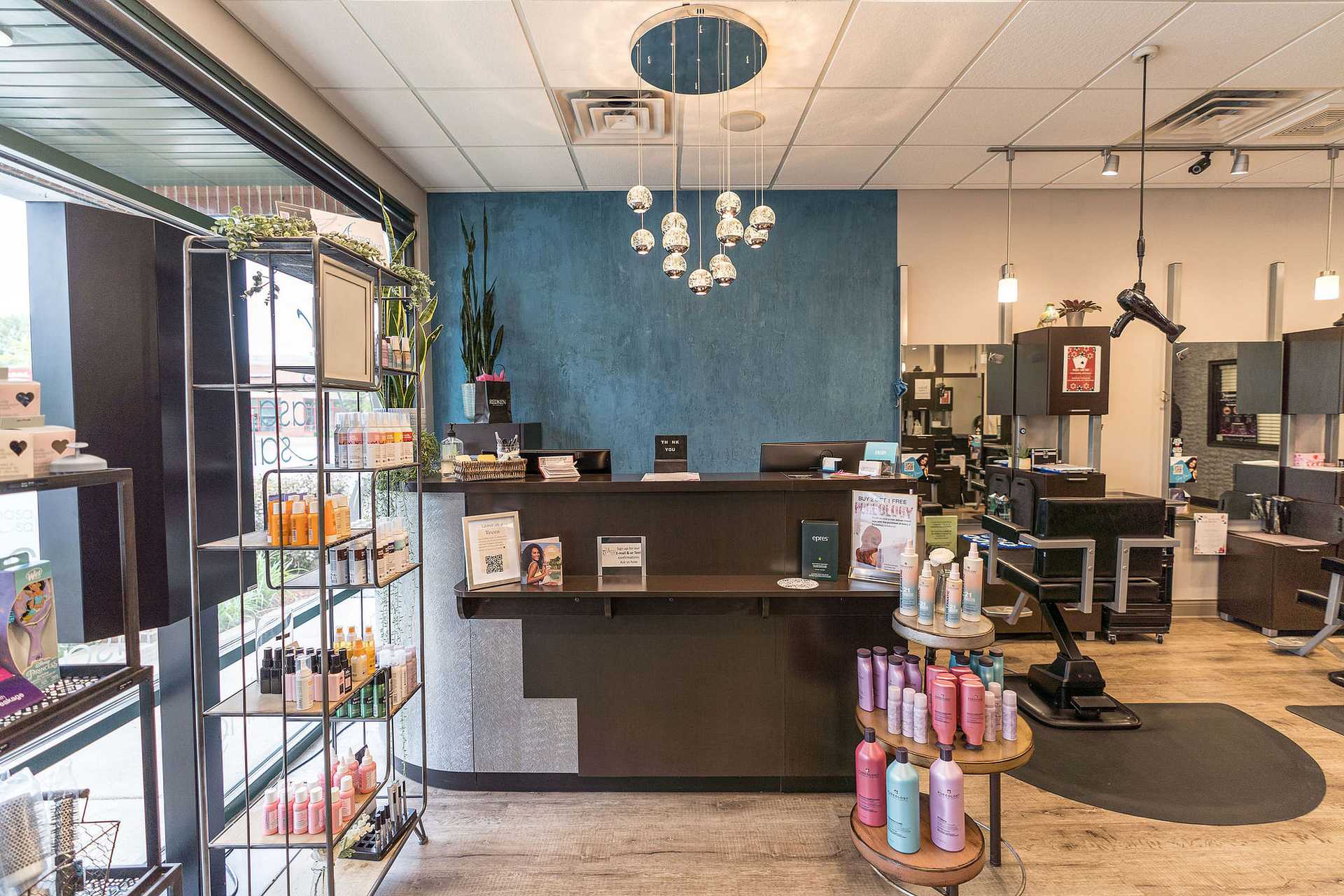 Modern hair salon interior with product shelves, modern decor, front desk, and styling area.